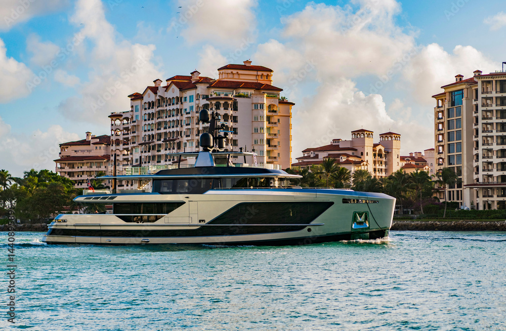 Obraz premium Motor boat yacht floating to marina. Luxury yacht boat at Fisher island. Summer vacation. Fisher island residential building and luxury yacht boat. Panorama view of Fisher island, Miami
