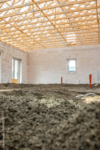 Obraz na płótnie Interior of a building under construction with white brick walls, exposed wooden truss roof, loose soil floor, and visible utility pipes. w salonie