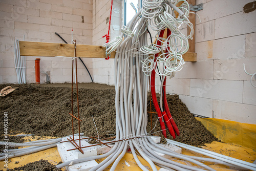 Obraz na płótnie Electrical conduit pipes in white and red emerge from a gravel covered floor, supported by wooden beams and metal rods in an unfinished building. w salonie