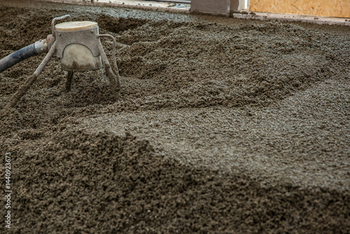 Obraz na płótnie Freshly poured concrete floor in an indoor construction site, with a leveling tool connected to a hose in use. Partially visible wall and window frame. w salonie