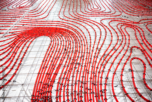 Obraz na płótnie Detailed view of red underfloor heating pipes secured to a metal grid, arranged in a curved pattern on a construction surface for concrete pouring. w salonie