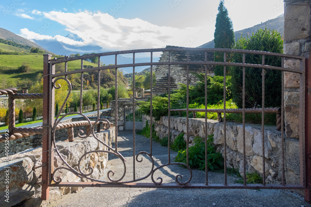 Old metal gate with scroll design framed by stonework.