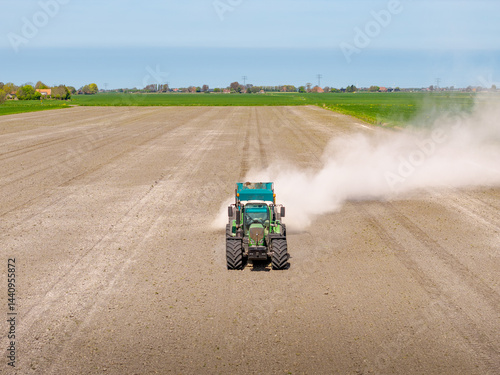 Tractor working on farmland spreading lime on dry soil in spring © Thomas