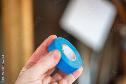 Hand and Electric Blue tape: handyman holding equipment