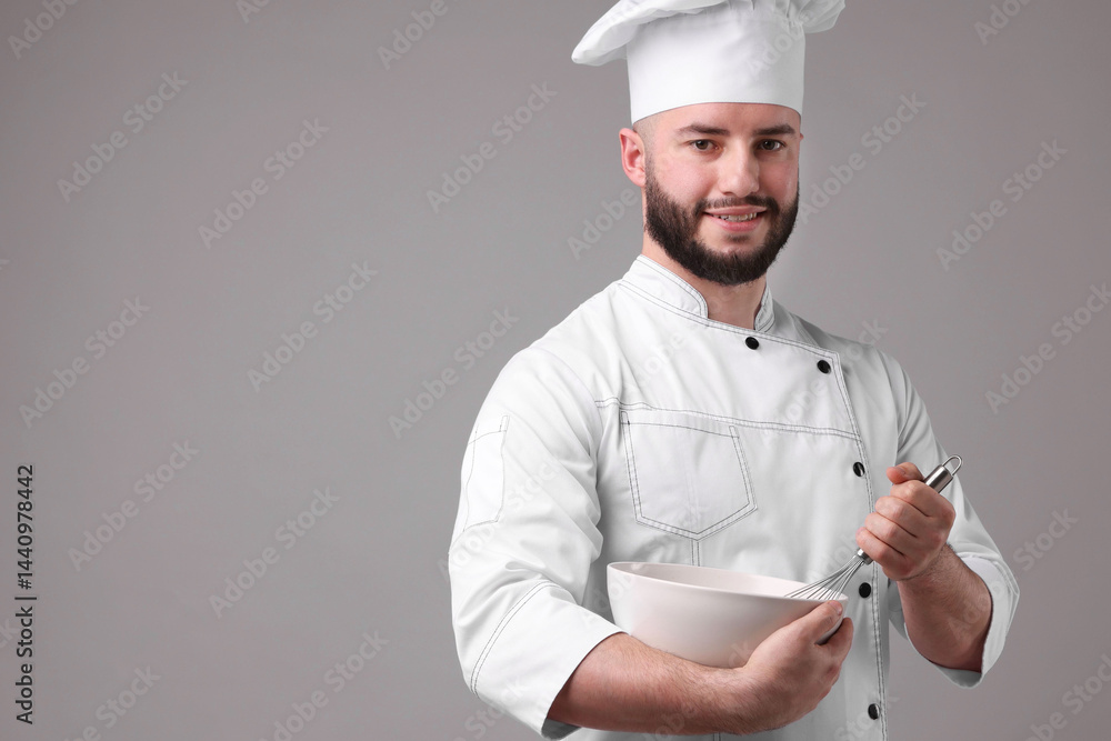 Happy confectioner in uniform holding whisk and bowl on light grey background Happy confectioner in uniform holding whisk and bowl on light grey background