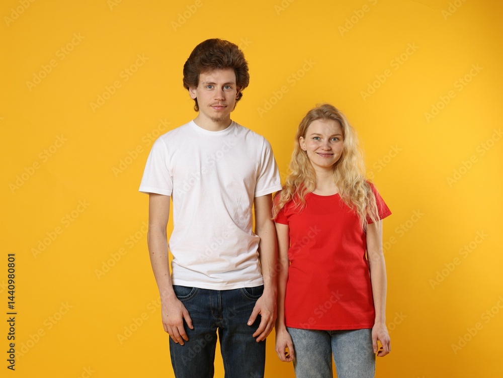 Fototapeta premium Young woman and man wearing blank t-shirts on orange background. Mockup for design