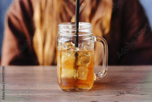 Refreshing iced tea in glass. Cold summer drink. Sweet beverage with ice cubes. Fresh cool refreshment. Relaxing drink on wooden table. Tasty iced tea in mason jar. Summer thirst background.
