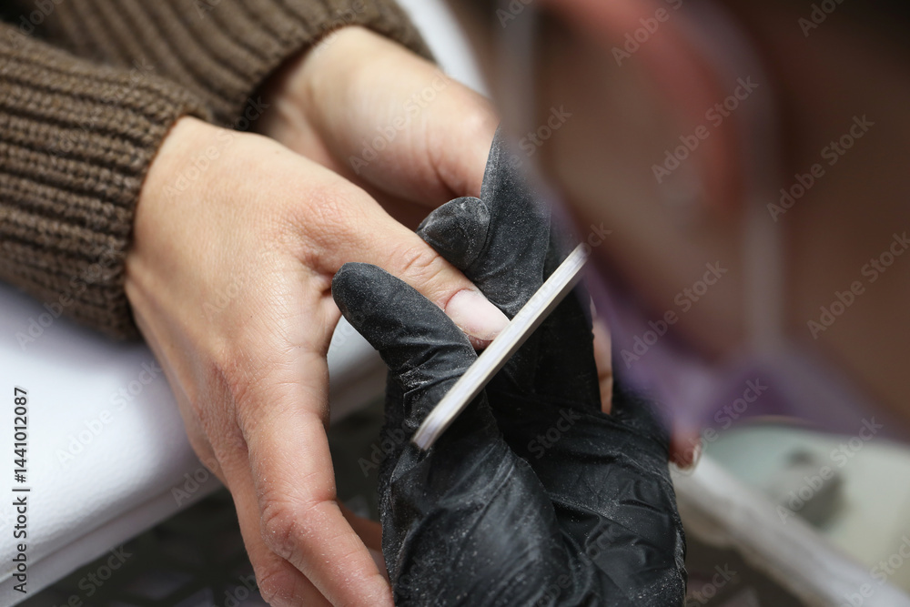 Professional manicure. Nail technician filing nails. Beauty salon service. Hand care treatment. Perfect nails creation. Relaxing beauty procedure. Elegant feminine hands. Hygiene and style focus.