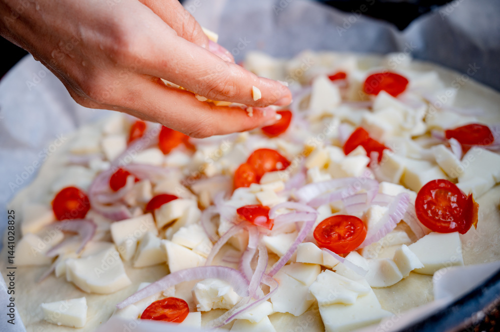 Close-up scene of female hands. Adding a mixture of three cheeses - mozzarella, parmesan and gorgonzola to the dough on the kitchen countertop. Making homemade pizza with three types of cheese - femal