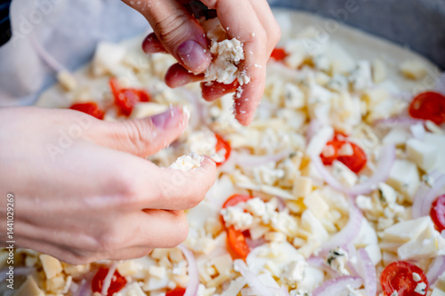 Obraz na płótnie Close-up scene of female hands. Adding a mixture of three cheeses - mozzarella, parmesan and gorgonzola to the dough on the kitchen countertop. Making homemade pizza with three types of cheese - femal w salonie