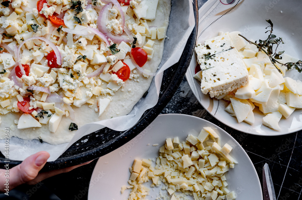 A homemade pizza in its raw form, assembled with toppings. The dough is uncooked but fully prepared with sauce, cheese, and fresh ingredients. The kitchen is cozy and softly lit, with utensils, bowls,