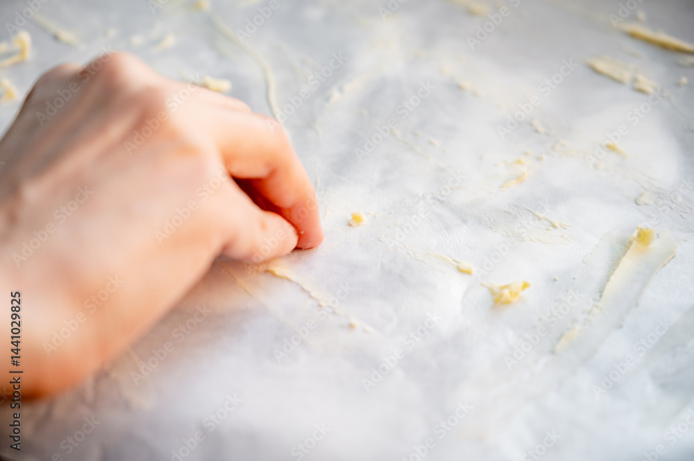Preparing parchment for baking pizza, greasing parchment with butter