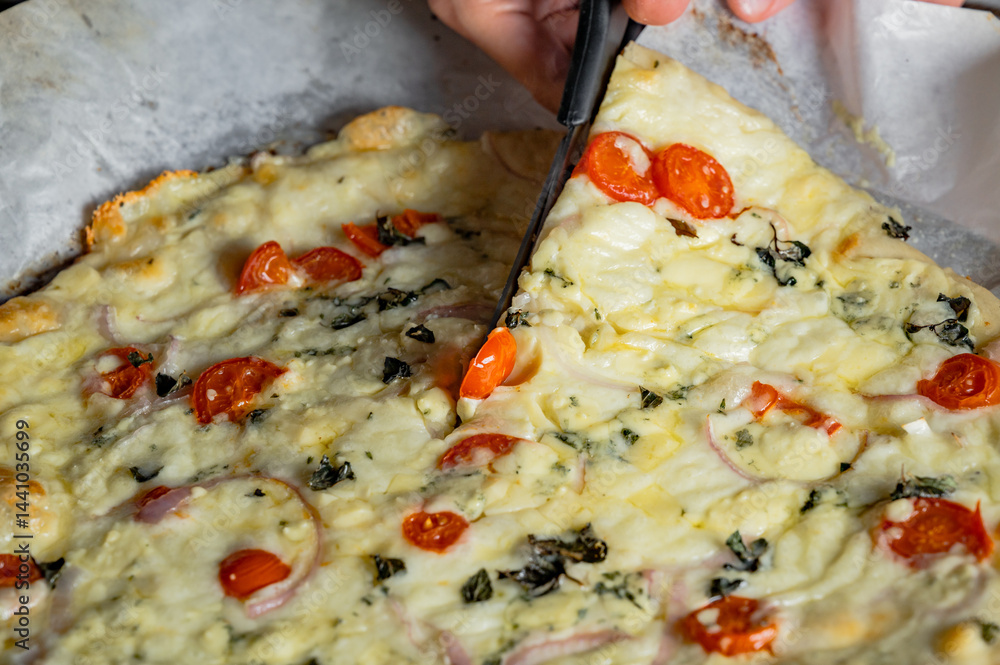 Cutting fresh homemade pizza with scissors