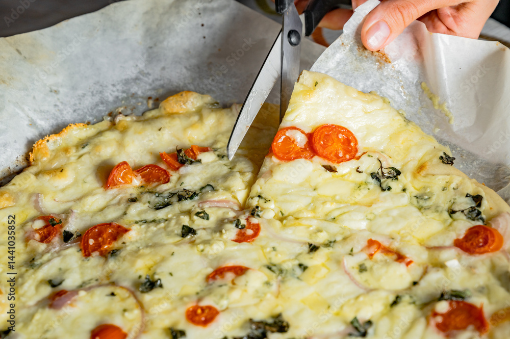 Cutting fresh homemade pizza with scissors