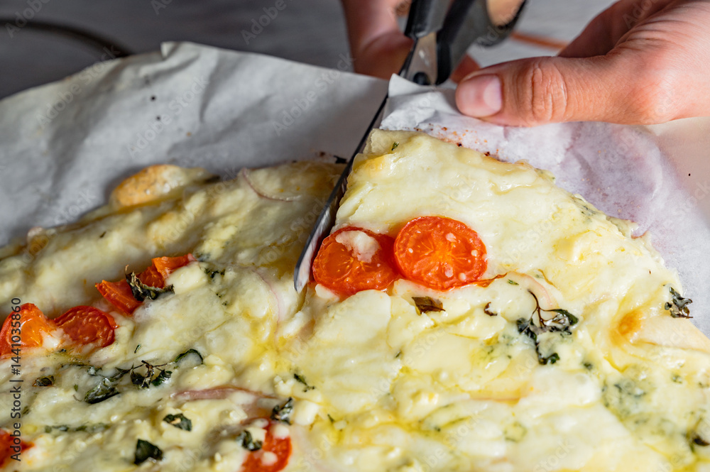 Cutting fresh homemade pizza with scissors