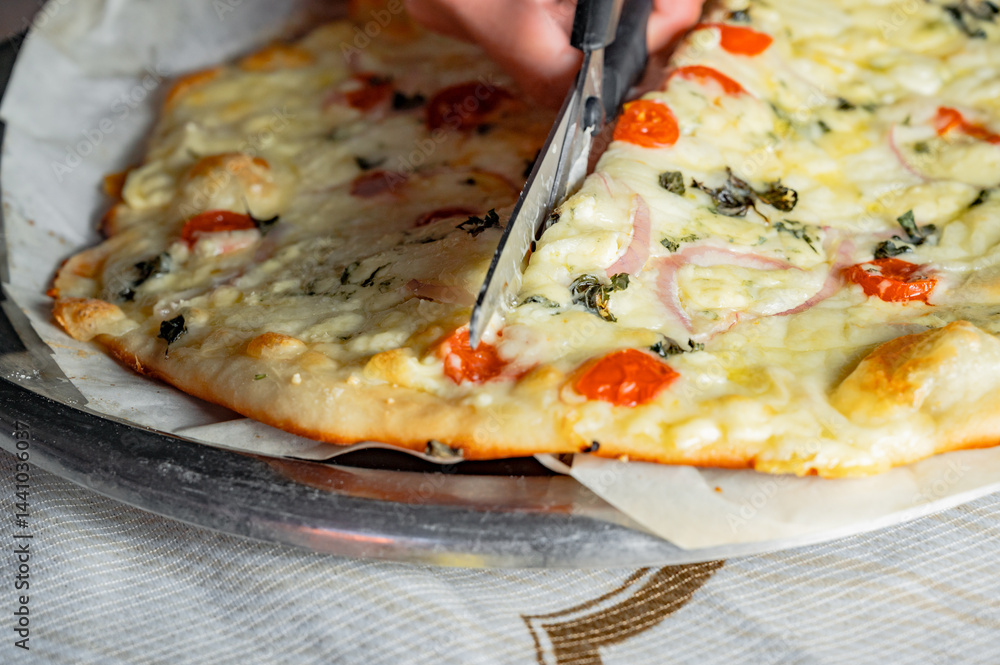Cutting fresh homemade pizza with scissors