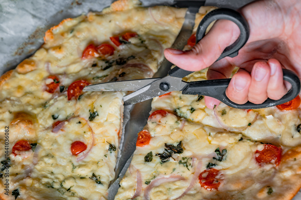 Cutting fresh homemade pizza with scissors