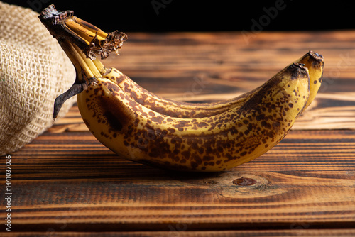 Ripe banana, almost overripe bananas on a rustic wooden surface and dark background, selective focus.