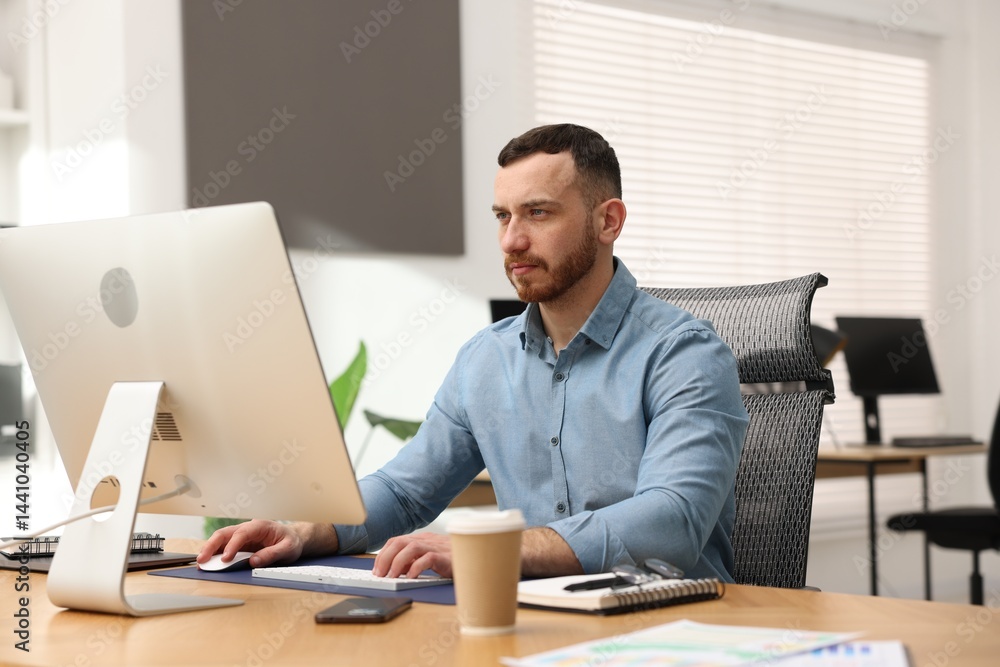 Man working on computer at desk in office Man working on computer at desk in office