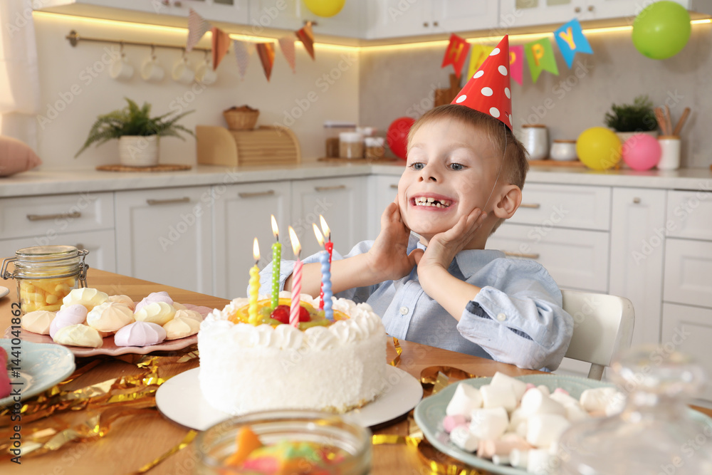 Cute little boy blowing out candles on birthday cake indoors. Surprise party Cute little boy blowing out candles on birthday cake indoors. Surprise party