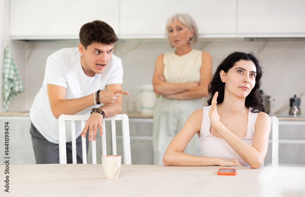 Obraz premium Elderly woman mother and young guy during family quarrel accuse adult daughter, prove her wrong