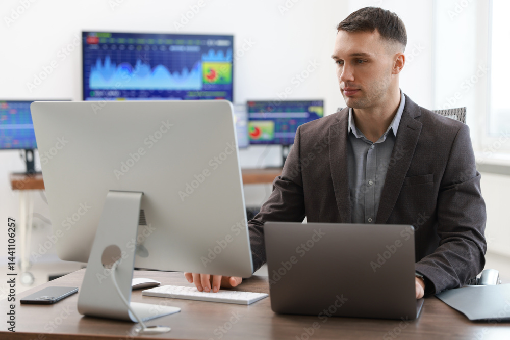 Financial trading specialist working on computer and laptop in office Financial trading specialist working on computer and laptop in office