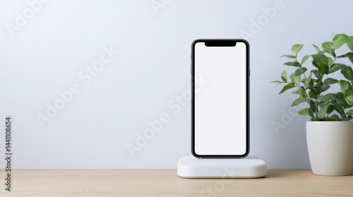 Obraz na płótnie Modern Smartphone on Wireless Charger with Green Plant on Wooden Desk w salonie
