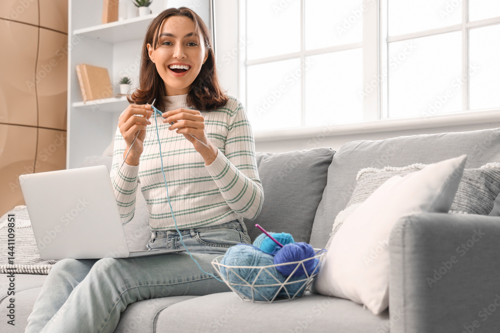 Young woman knitting with needles and laptop at home Young woman knitting with needles and laptop at home