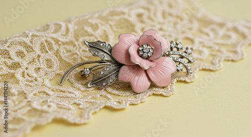 A delicate pink floral brooch with sparkling crystals, resting on a vintage lace background.