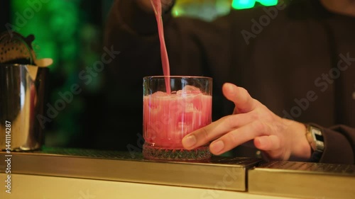 The bartender pours the finished cocktail into a glass