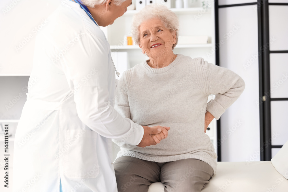 Obraz premium Sick senior woman with back pain visiting doctor in clinic