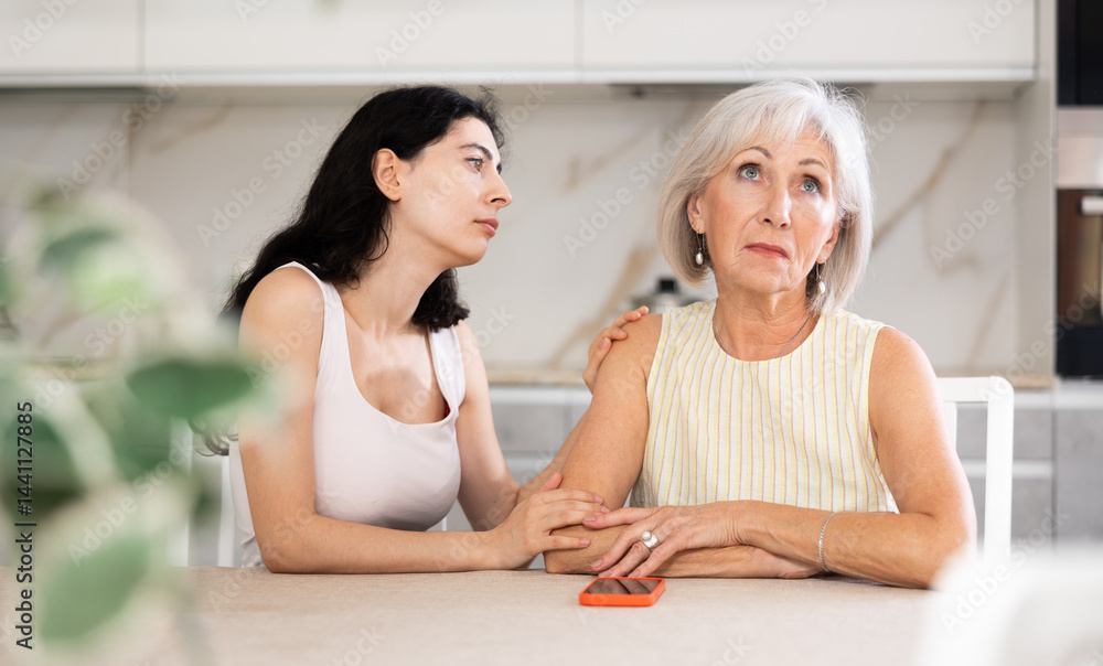 Young woman apologizes to older woman after argument in kitchen at home