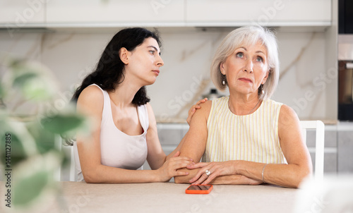 Obraz na płótnie Young woman apologizes to older woman after argument in kitchen at home w salonie