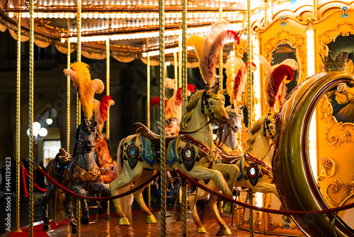Colorful carousel horses with feathers in nighttime amusement park.