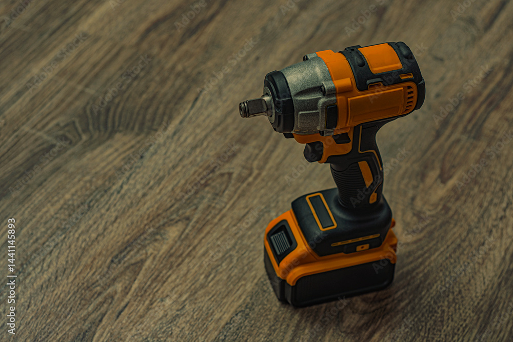 Obraz premium A powerful cordless impact wrench on a wooden surface. Electric tool for construction and automotive repair.