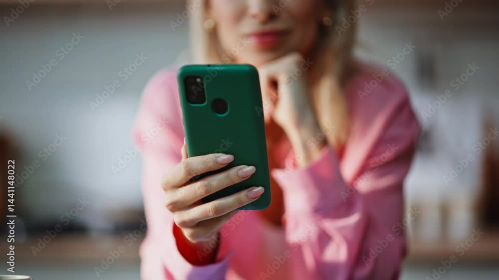 Lady hand holding cellphone reading book online at kitchen interior closeup Lady hand holding cellphone reading book online at kitchen interior closeup