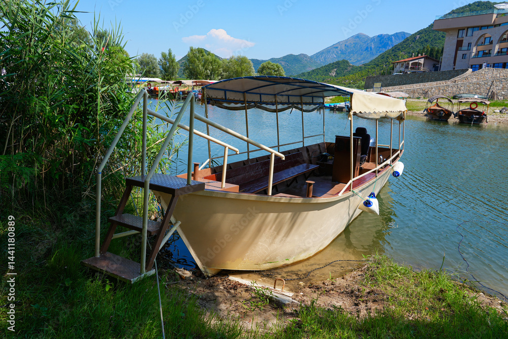 Obraz premium Sightseeing boat moored on the banks of the channel linking Virpazar to the Lake Skadar in Montenegro