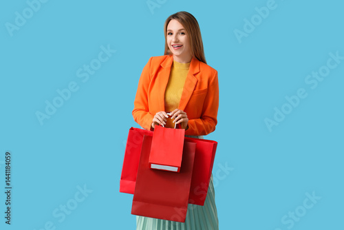 Fotografie Beautiful young happy woman with shopping bags on blue background