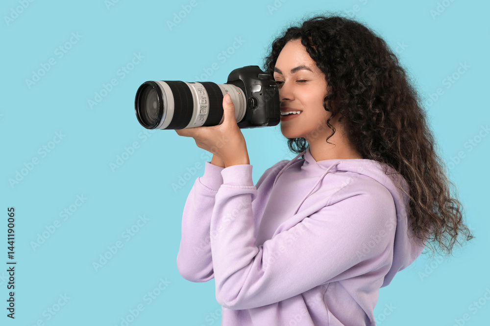 Female African-American photographer with camera on blue background Female African-American photographer with camera on blue background