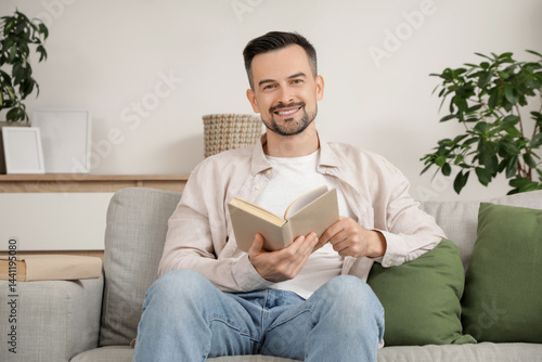 Handsome man reading book o...