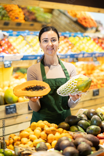 Obraz na płótnie Female grocery store worker offers papaya in grocery department of the supermarket w salonie