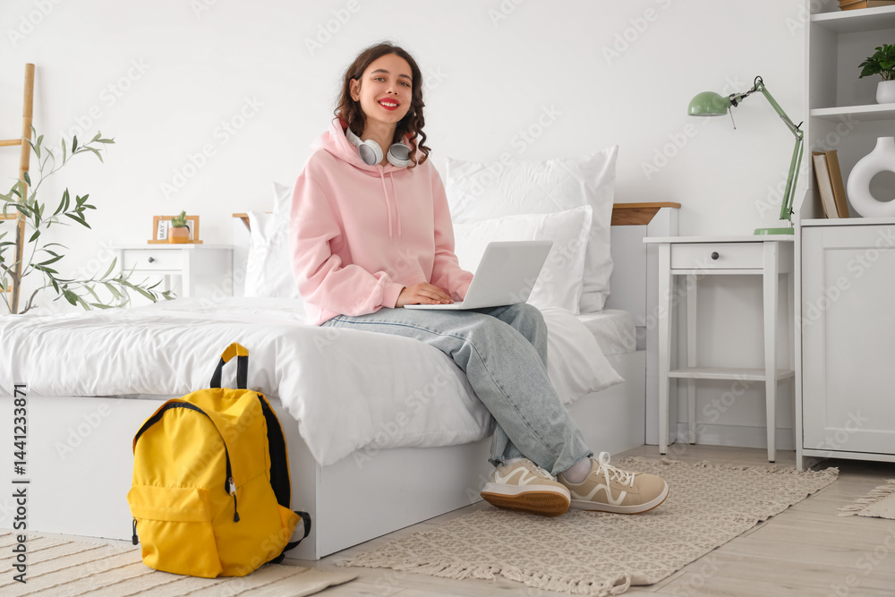 Female Indian student studying with laptop in bedroom