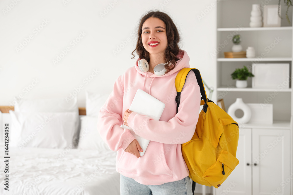 Female Indian student with backpack and laptop in bedroom