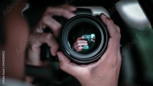 A person holding a camera with a reflection in the lens taking a photograph