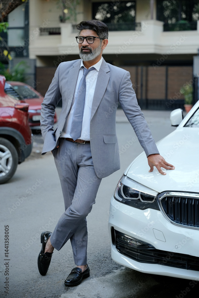 Indian businessman standing in formal suit while standing at park outdoors Indian businessman standing in formal suit while standing at park outdoors