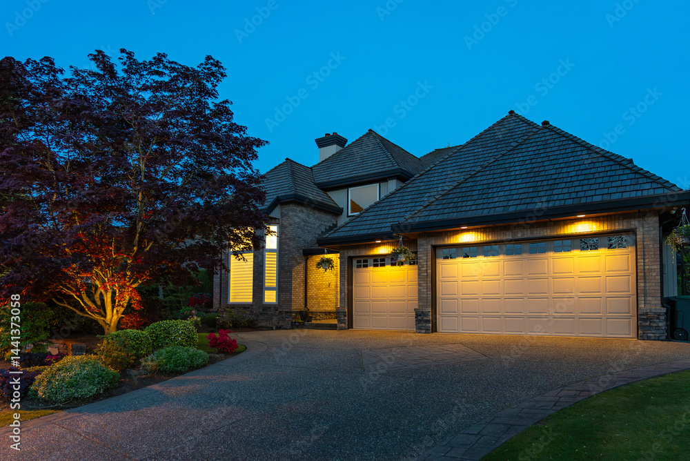 Fototapeta premium Garage door in luxury house with trees and nice landscape in Spring in Vancouver, Canada, North America. Night time on April 2025.