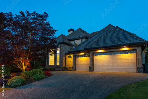 Garage door in luxury house with trees and nice landscape in Spring in Vancouver, Canada, North America. Night time on April 2025.