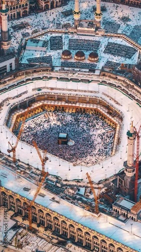 Dynamic hyperlapse showing a crowded view of pilgrims performing Tawaf around the Kaaba at the Grand Mosque in Mecca, Saudi Arabia from an aerial perspective
