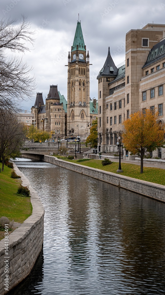 Naklejka premium Autumnal view of the Parliament Buildings reflected in a canal, showing fall colors and a tranquil scene. Ideal for tourism brochures or nature photography