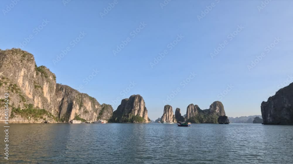 A wide scenic view of Ha Long Bay, Vietnam, with towering limestone islands and several boats gliding on the sea. A wide scenic view of Ha Long Bay, Vietnam, with towering limestone islands and several boats gliding on the sea.
